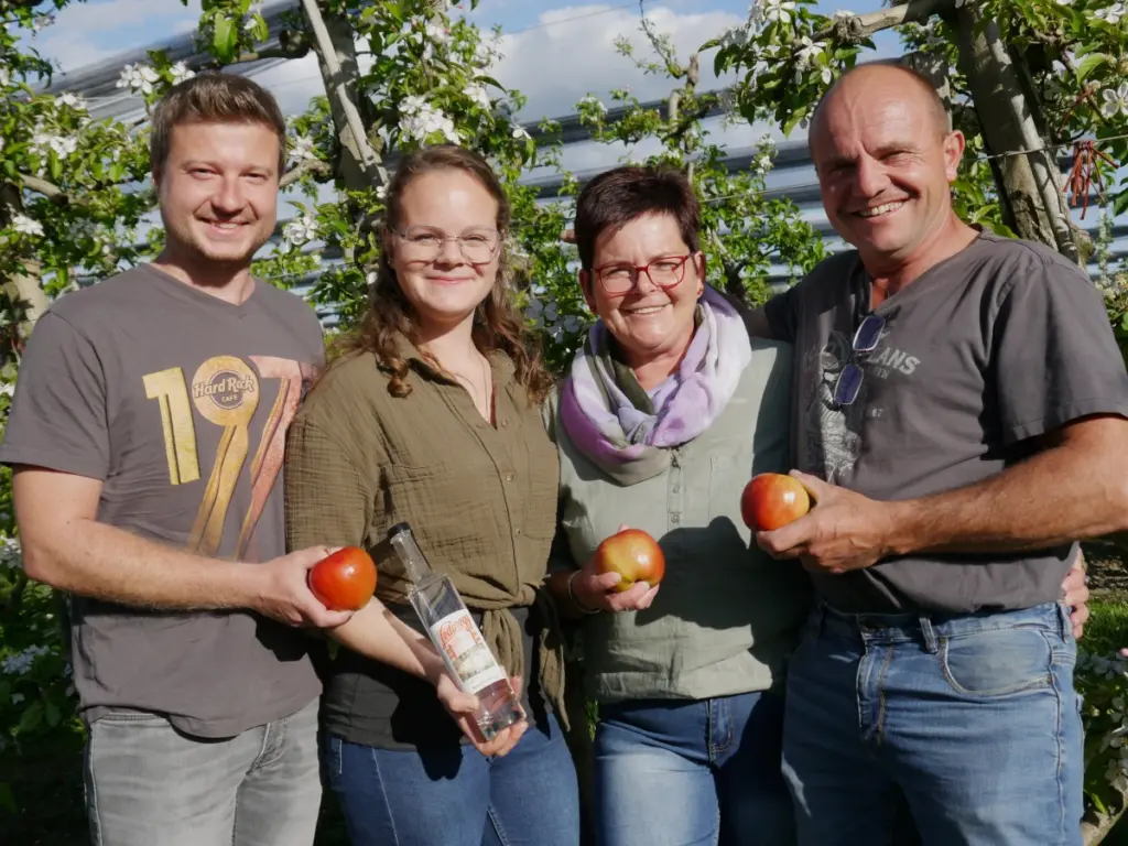 ie gesamte Familie Ledinegg im Obstgarten: Zwei Generationen des Familienbetriebs präsentieren gemeinsam frische Äpfel und selbst gebrannten Edelbrand.